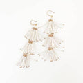 A pair of Aster Fleur earrings featuring glass beads in white and gold colors, displayed on a white background.