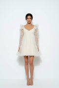 Dani effortless bridal dress Woman wearing a white dress with sheer sleeves on a white background
