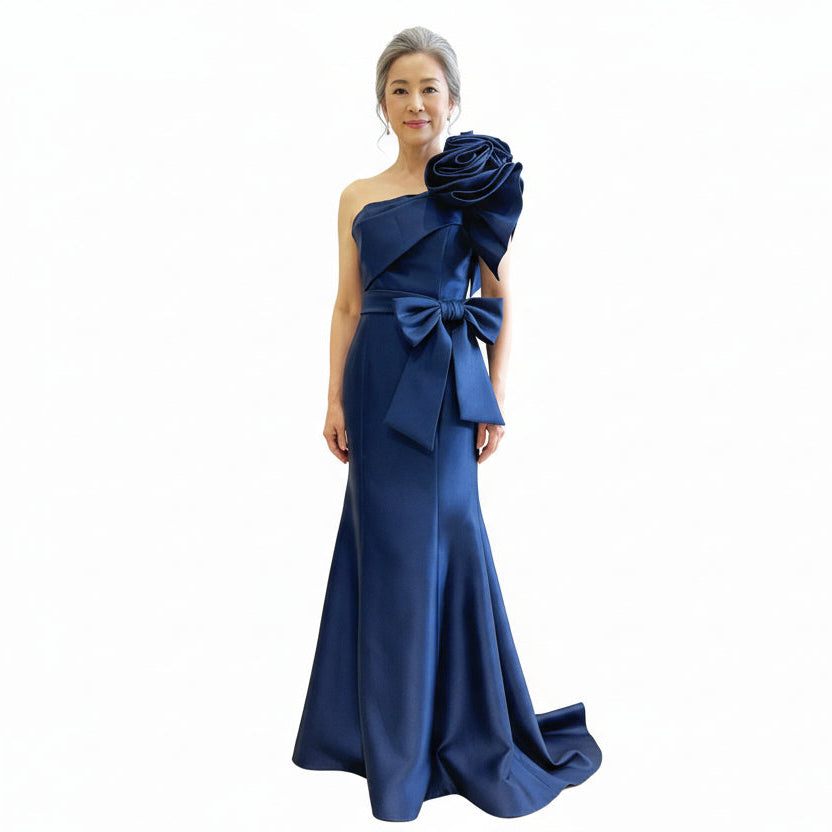 Eve mother of the bride dress Woman wearing a blue evening gown with a large bow and floral detail on a white background
