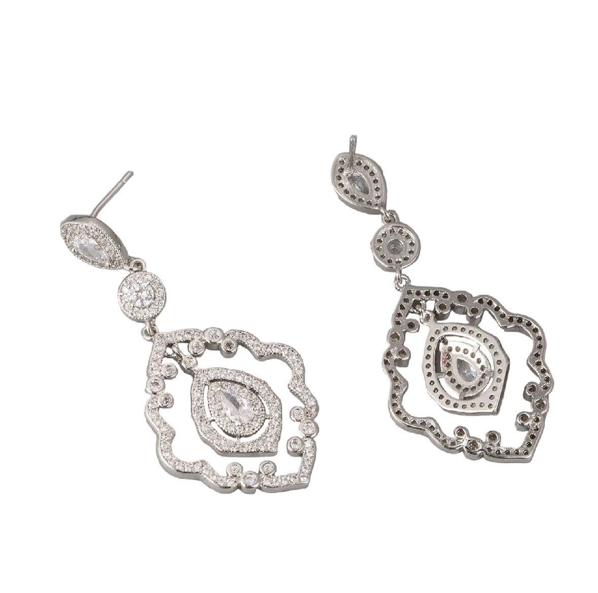 Cheveux Extensions by Mar Statement dangles feature ornate, silver-toned designs with intricate openwork and multiple oval and teardrop-shaped white gemstones, ideal as bridal earrings, shown on a white background.