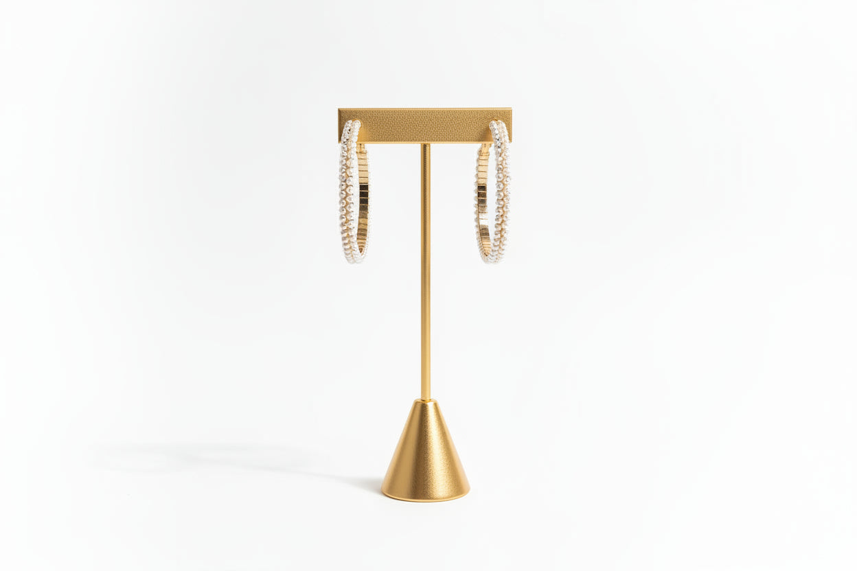 Cheveux Extensions by Mar’s Double Pearl Gold Hoops are showcased on a minimalist white stand set against a textured white background.