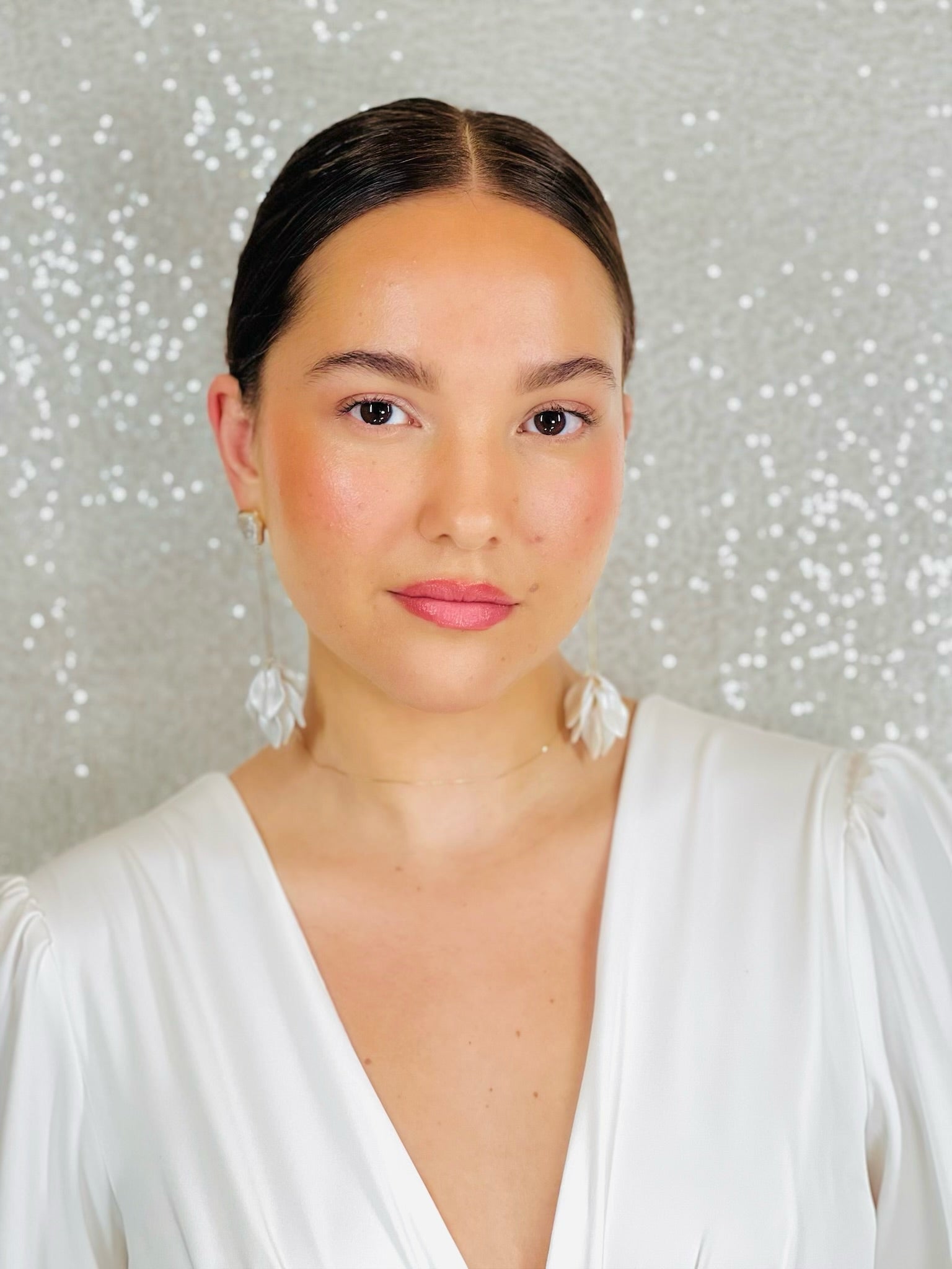 Woman wearing a white dress with a sparkling silver background