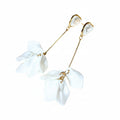 Pair of white floral earrings with gold accents on a light background
