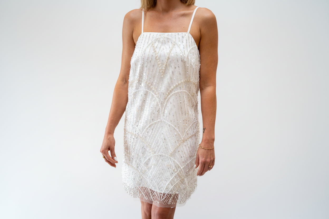White lace dress worn by a person on a neutral background