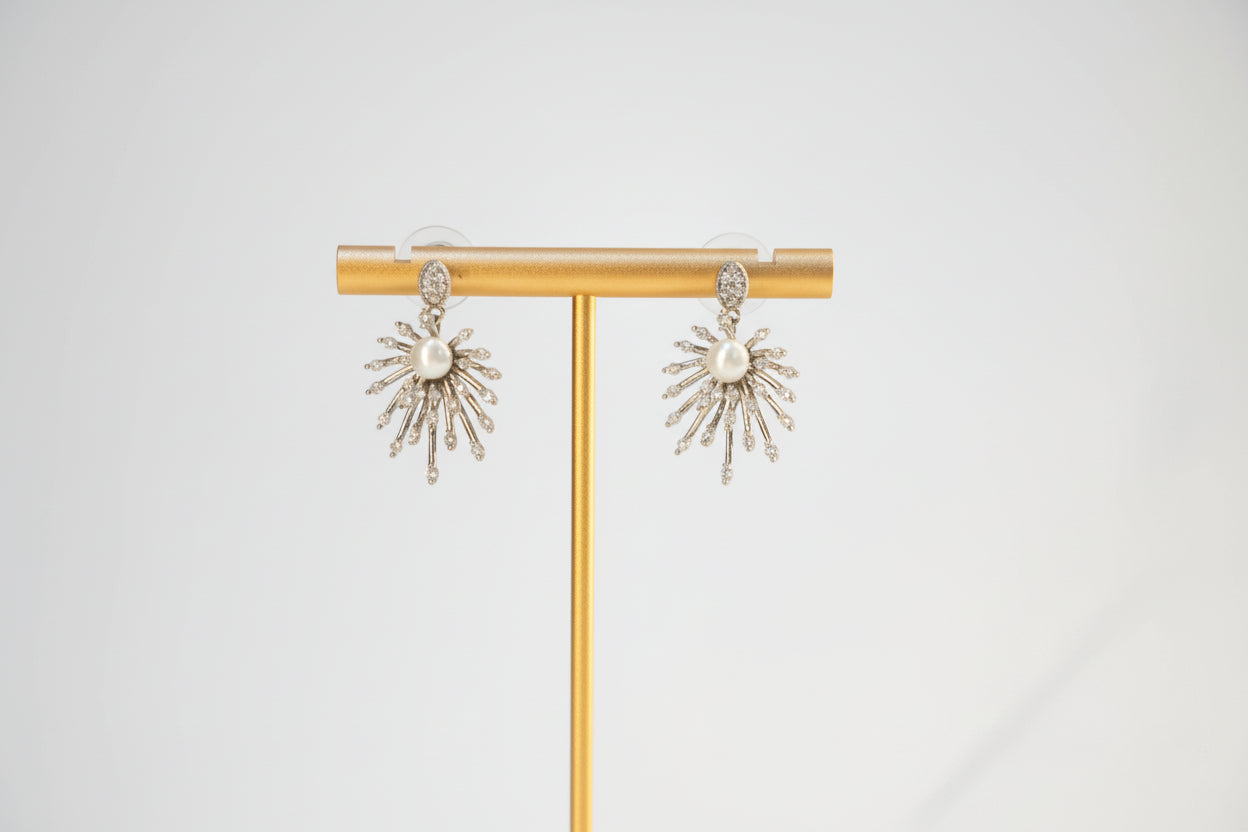Gold earring stand with sun-shaped earrings on a white background