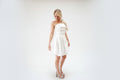Woman wearing a strapless white dress against a white curtain background