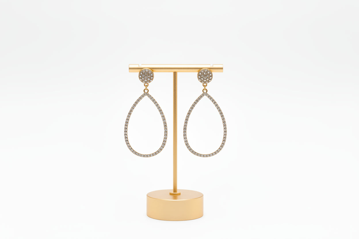 A pair of gold teardrop stud earrings with rhinestone embellishments, displayed on a gold stand